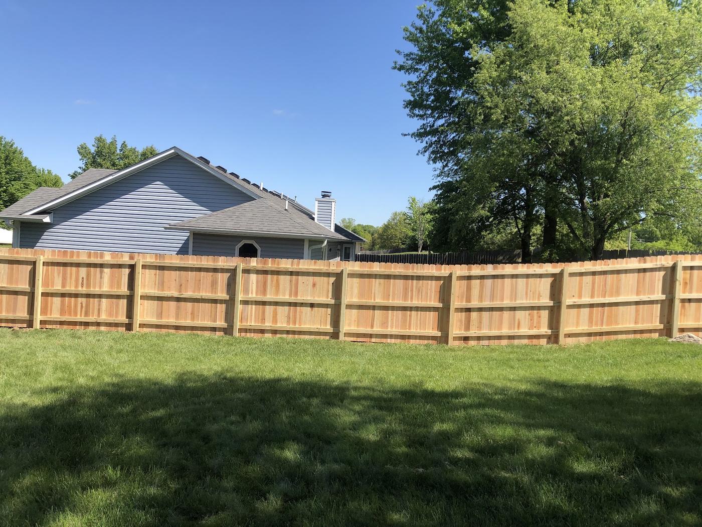 A completed privacy fence running the length of a back yard in Columbia, natural unstained boards on rails under a clear sky
