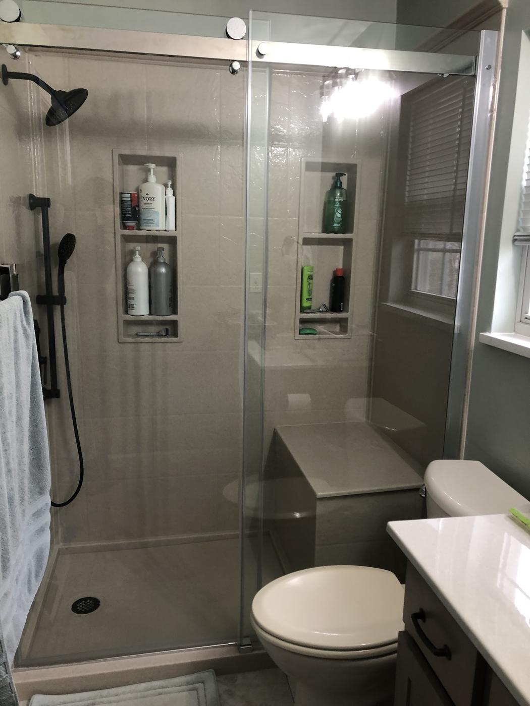 The finished shower stall: a glass slider, two built-in niches, a bench seat and matte black fittings